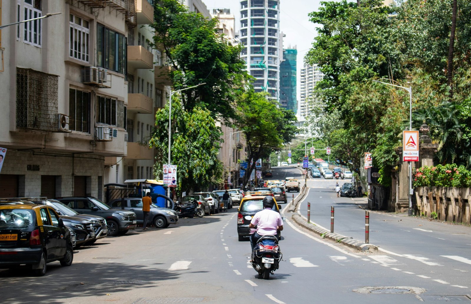A man riding a motorcycle down a street next to tall buildings